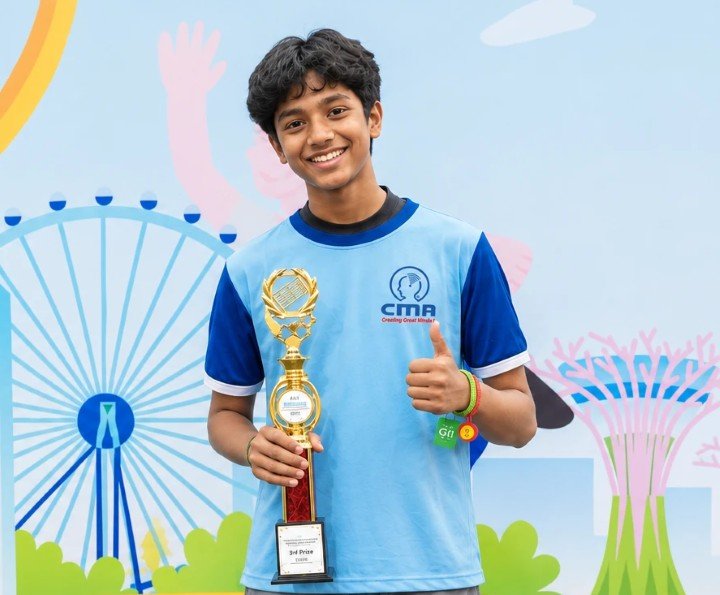 A smiling CMA student in his CMA T-shirt holding a trophy and giving a thumbs-up